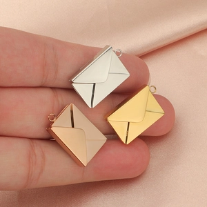 Polished mirror-finish envelope pendants in gold, silver, and rose gold on pink silk