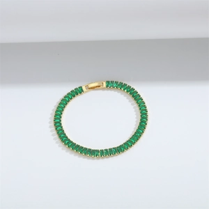 Detail shot of a gold tennis bracelet featuring rectangular green zircon stones in a row