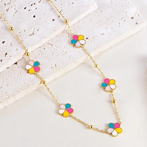 Collier doré avec pendentifs fleurs en émail coloré sur une surface en pierre blanche