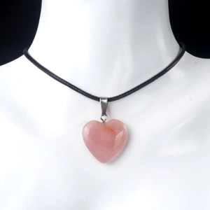 Pink heart-shaped crystal stone necklace with black cord on white mannequin