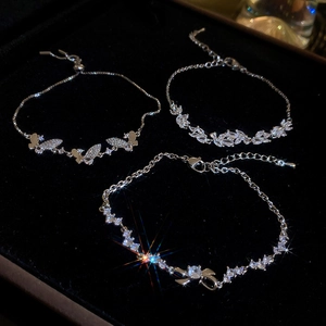 Detailed macro shot of zircon butterfly and leaf design silver bracelets on black velvet