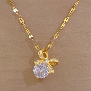 Detail of gold bow necklace featuring a large round crystal pendant and micro-inlaid stones