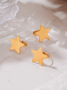 Detailed macro view of three matte 18k gold plated star rings on a marble surface