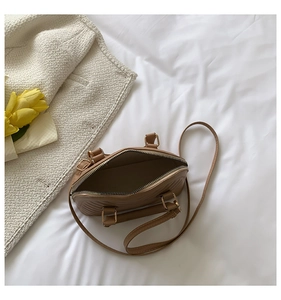 Close-up of brown quilted shell bag with gold hardware and interior storage space