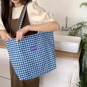 Detail of blue and white checkered knit tote bag with purple label for daily styling
