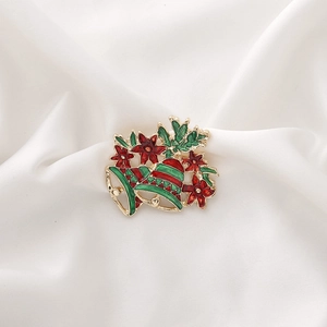Christmas brooch with red flowers, green leaves, and golden bells on white silk
