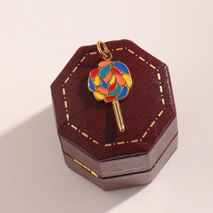 Close-up of a gold lollipop pendant with colorful enamel on a vintage jewelry box