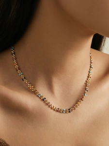 Detail of gold chain necklace with colorful enamel leaf charms on female model