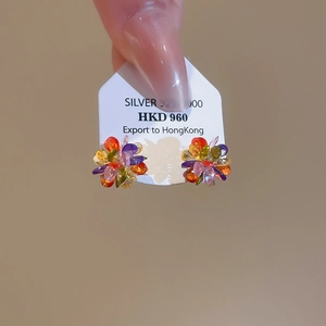 Macro shot of colorful crystal flower earrings on silver card held by hand
