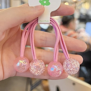 Close-up of four pink handmade elastic hair ties with glitter resin ball charms