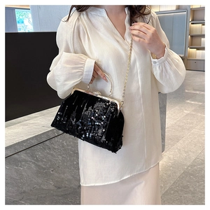 Detail of black sequined evening bag with rhinestone clasp and metal handle on white shirt