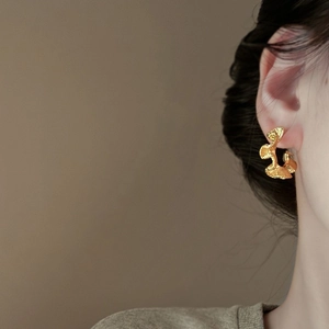 Detailed close-up of golden irregular floral earrings showing organic hammered metal texture
