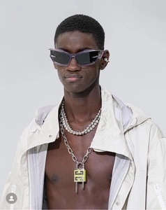Detail of purple cat-eye sunglasses and luxury metal padlock necklace on a model