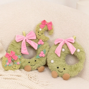 Close-up of plush green Christmas wreaths with cute faces on a soft beige sofa