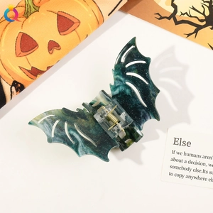 Detailed shot of bat-shaped hair claw in dark green marble finish with glitter