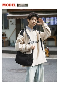 Outdoor street style shot showing a black nylon messenger bag with an adjustable strap