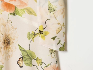 Détail de l'imprimé floral et papillon sur robe crème sans manches avec coutures
