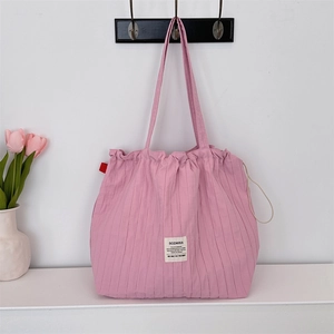 Detailed view of pink pleated canvas tote bag with woven texture and a white label