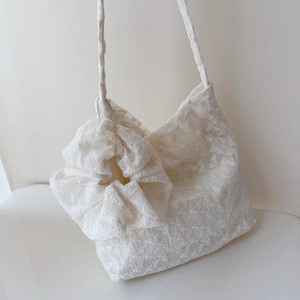 Detail of white floral lace tote bag featuring a large decorative 3D flower on the strap