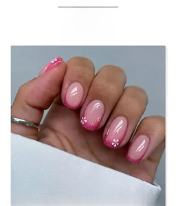 Macro shot of French pink gradient press-on nails with glitter tips and floral art