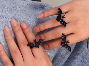 Macro shot of gothic matte black bat rings on fingers with denim background detail