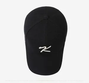 Top-down view of black cotton baseball cap featuring white K letter embroidery detail
