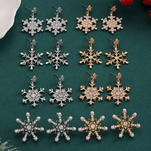 Set of 8 pairs of Christmas snowflake stud earrings with crystals and pearls on green fabric