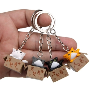 Detail of four colorful 3D cartoon cats in boxes keychains held in hand with metal rings
