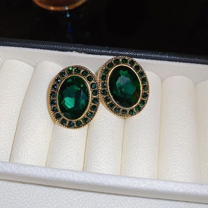 Orecchini vintage ovali dorati con cristalli verde scuro in una scatola regalo bianca