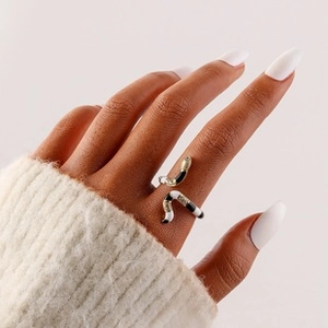 Detail of a gold adjustable ring with black and white enamel wavy patterns on model