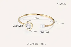 Close-up of golden stainless steel cuff bracelet with square crystal and white shell pearl