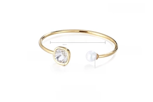Close-up of golden stainless steel cuff bracelet with square crystal and white shell pearl