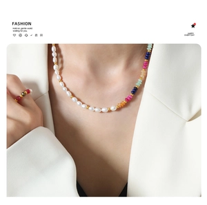 Detail of baroque freshwater pearl and colorful stone beaded necklace on a white blazer