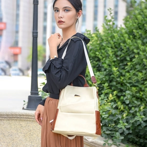 Detail of a beige and brown crocodile print backpack with a wide canvas shoulder strap