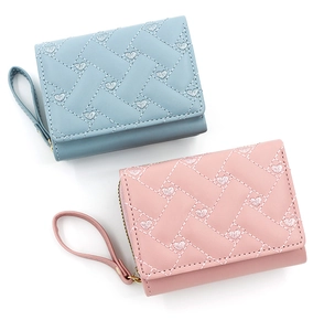Close-up of heart embroidery and quilted texture on light blue and pink PU leather wallets