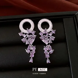 Elegant silver circle earrings with purple pear-cut zircon tassels on black leather background