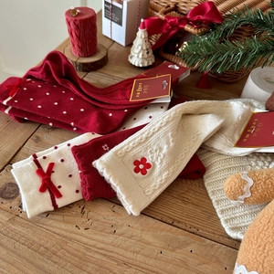 Festive red Christmas socks with velvet bows and embroidered flowers on wooden background