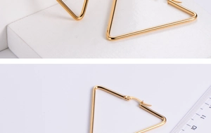 Macro detail of large gold triangle hoop earrings showing size measurement and high polish