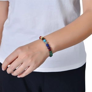Detail of multi-color natural stone chakra bracelet worn on wrist with elastic band