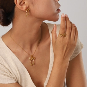 Close-up of golden bow-shaped jewelry set including earrings and necklace on model