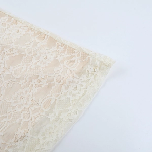 Detailed macro view of ivory lace fabric with intricate floral embroidery patterns