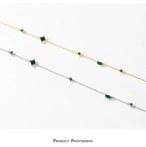 Detail view of gold and silver necklaces with green emerald-cut zircon pendants