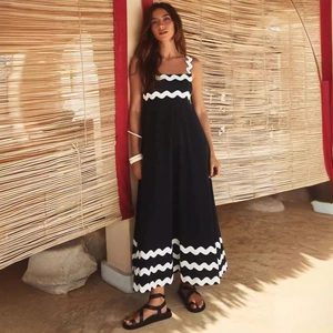 Elegant sleeveless long dress in black with white scalloped trim and printed floral details