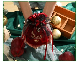 Detail of red velvet Christmas drawstring gift bag with gold Merry Christmas print