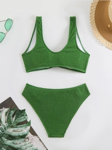 Detailed view of green crinkle fabric bikini set with tropical vacation accessories