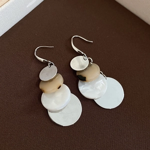 Detail of layered acrylic earrings with leopard print, shell texture and brushed metal