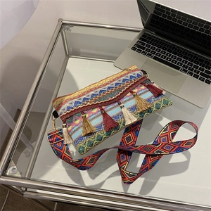 Detail of bohemian knit crossbody bag featuring colorful tassels and patterned strap