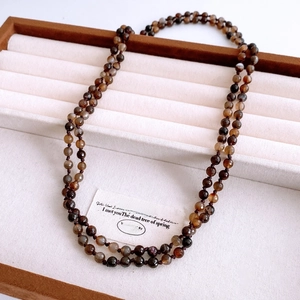 Close-up of vintage agate beaded necklace with faceted dark brown stones in display tray
