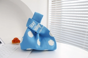 Close-up of blue polka dot knit tote bag featuring 'Stay HUNGRY' text on handle