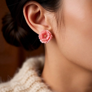 Elegant 3D pink resin flower stud earrings with golden stamens shown on a model